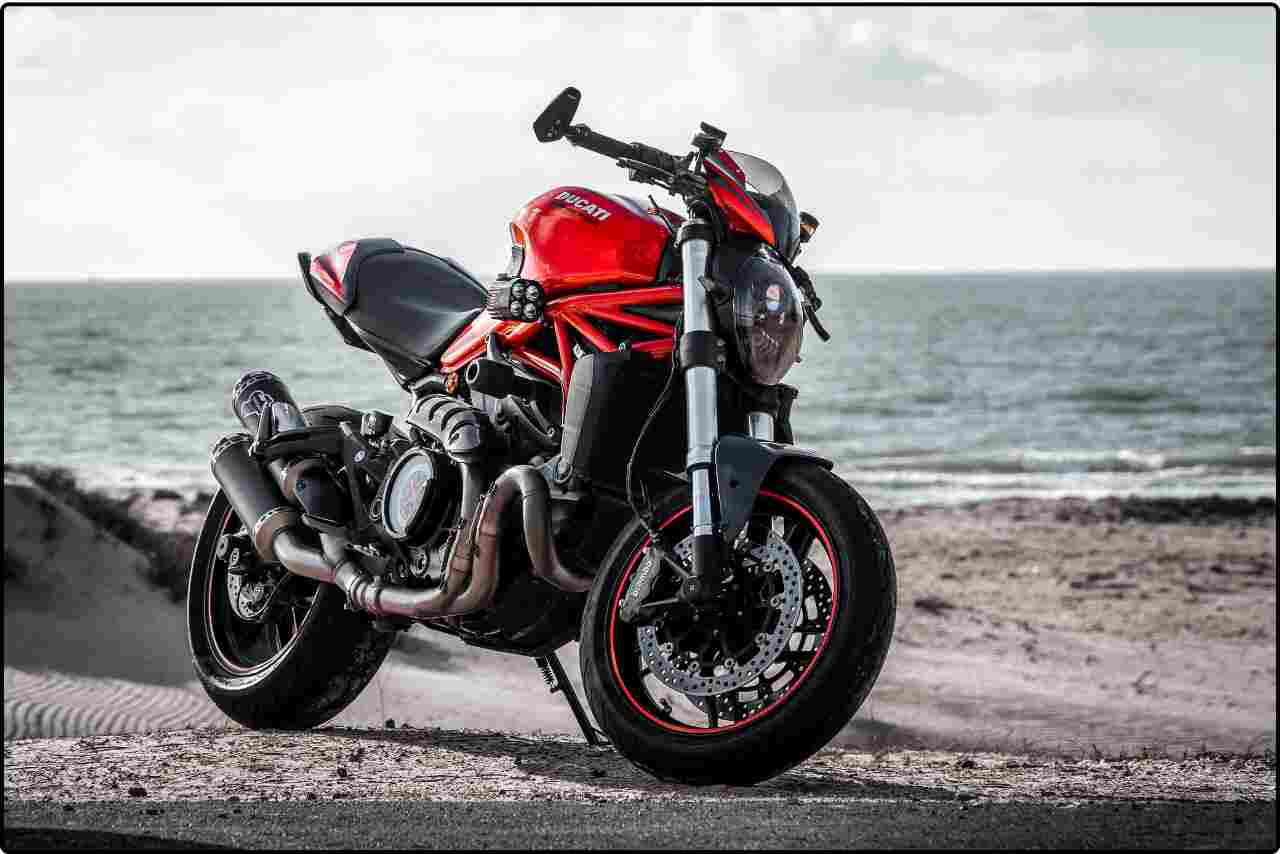 Motorcycle parked on a sandy beach with ocean waves in the background.